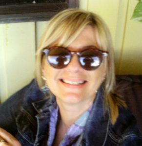 A person wearing a pair of brown sunglasses smiling at the camera